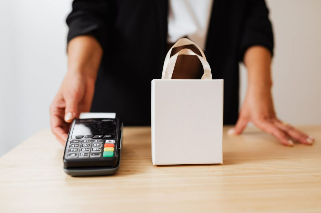 Countertop card payment terminal on a shop counter beside a paper bag