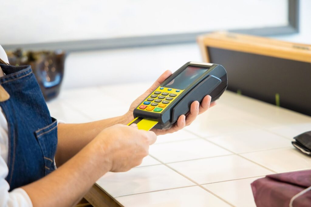 Card being inserted into a handheld payment terminal at a shop counter