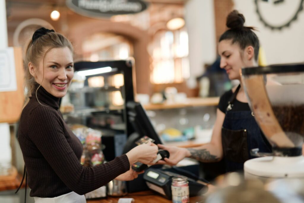 Customer making a contactless card payment at a busy café counter
