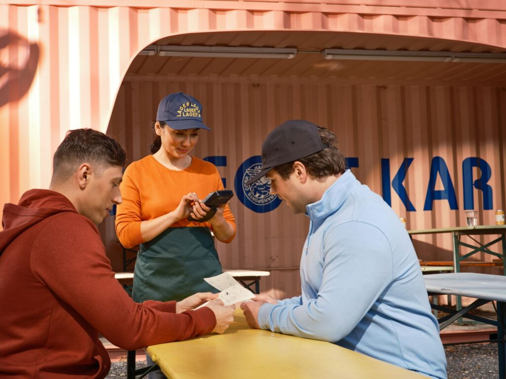 Staff member taking an order on a handheld device at an outdoor café table