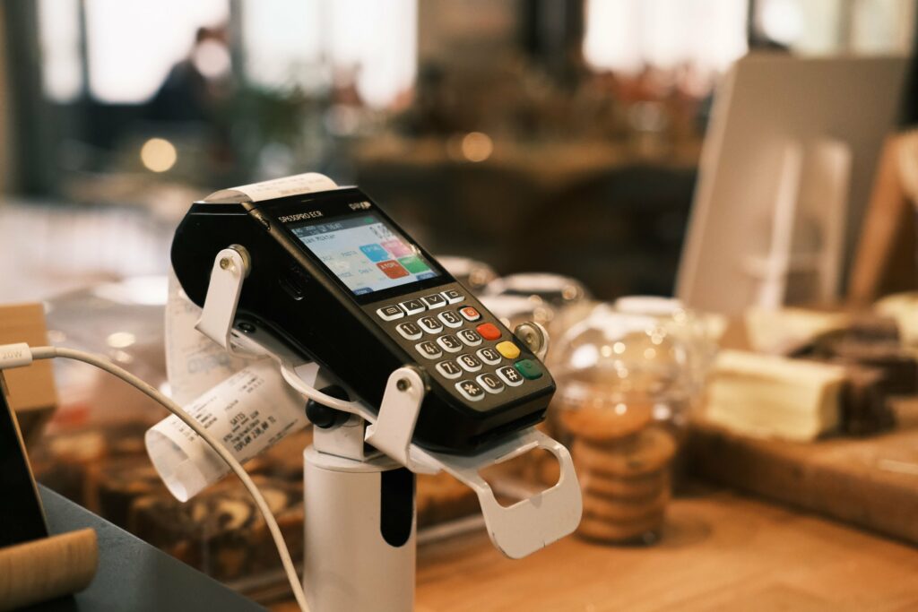 Card payment terminal with a lit touchscreen on a cafe counter